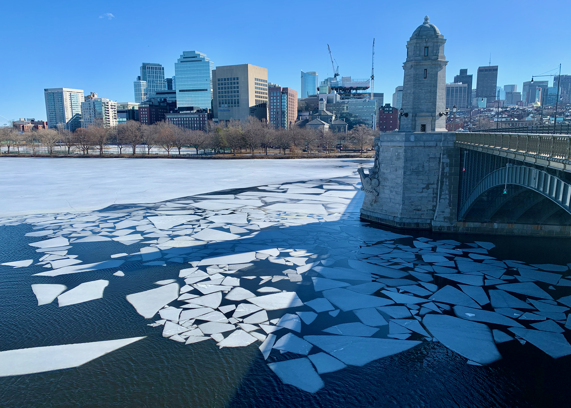 The Charles River partially frozen over, with shattered fragments of ice forming a mosaic pattern near the Longfellow Bridge that goes over the river.
